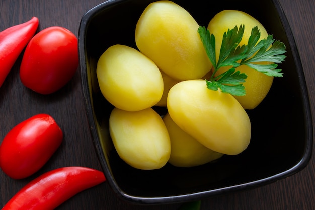 Patate bollite con peperoncino e pomodori su fondo scuro