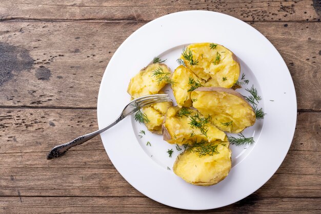 Patate bollite su un piatto bianco e una tavola di legno