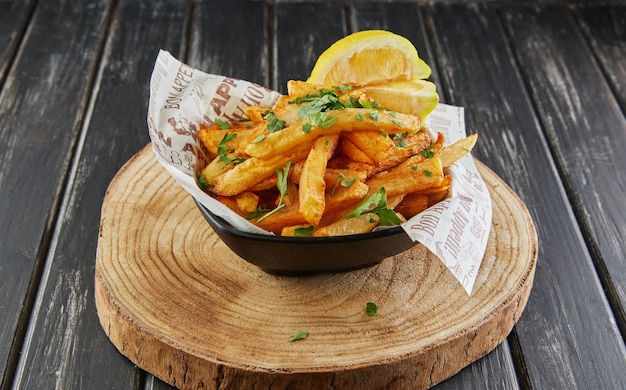 Patate con prezzemolo e limone fritte in olio su tavola di legno che servono nella caffetteria