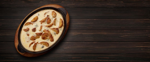 Patate cotte nel formaggio in padella su fondo di legno