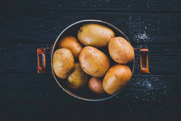 Patate crude su fondo di legno nero Cottura Spazio libero per il testo Vista dall'alto