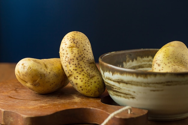 Patate e patate affettate sul tavolo di legno. Messa a fuoco selettiva