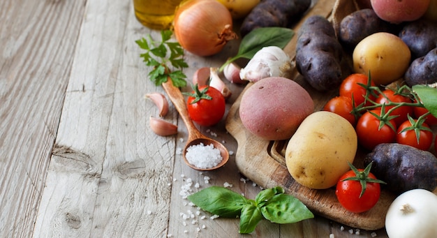 Patate e verdure crude su una tavola di legno