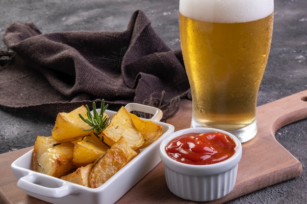 Patate fritte al forno con rosmarino, sale grosso, olio d'oliva e paprika speziata in una padella di ferro e una pinta di birra.