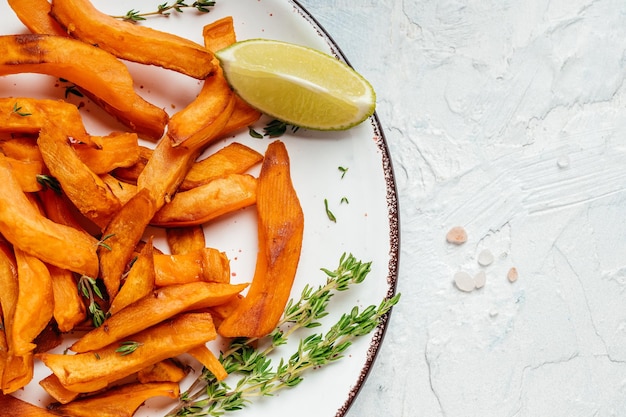 Patate fritte all'arancia fatte in casa con lime ed erbe aromatiche, sfondo ricetta alimentare. Avvicinamento