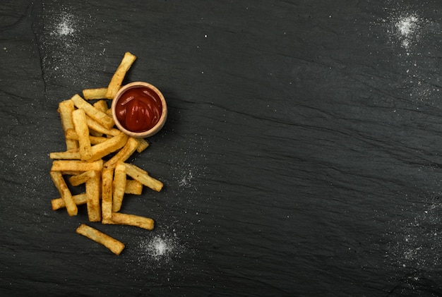 Patate fritte con ketchup sul tavolo scuro