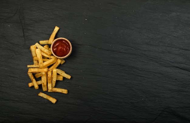 Patate fritte con ketchup sul tavolo scuro