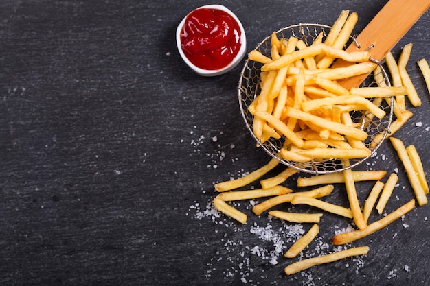 Patate fritte con ketchup sul tavolo scuro