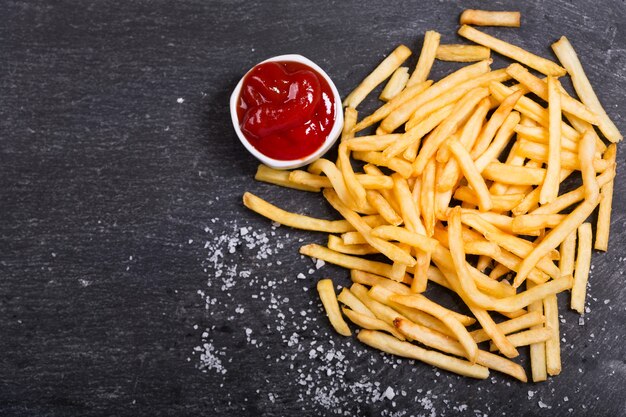 Patate fritte con ketchup sul tavolo scuro