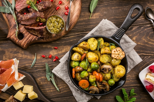 Patate fritte con verdure ed erbe su fondo di legno.