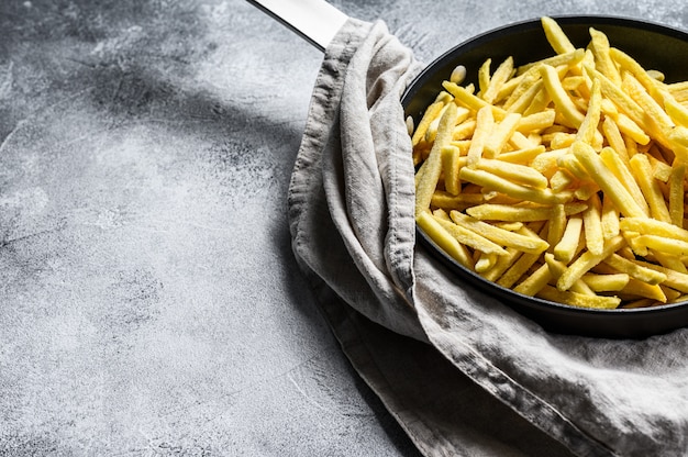 Patate fritte congelate in una padella. Sfondo grigio. Vista dall'alto. Spazio per il testo