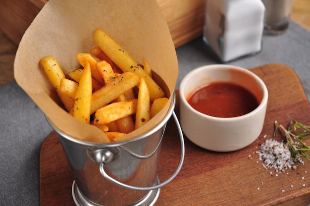 Patate fritte in un secchio di metallo con salsa di pomodoro