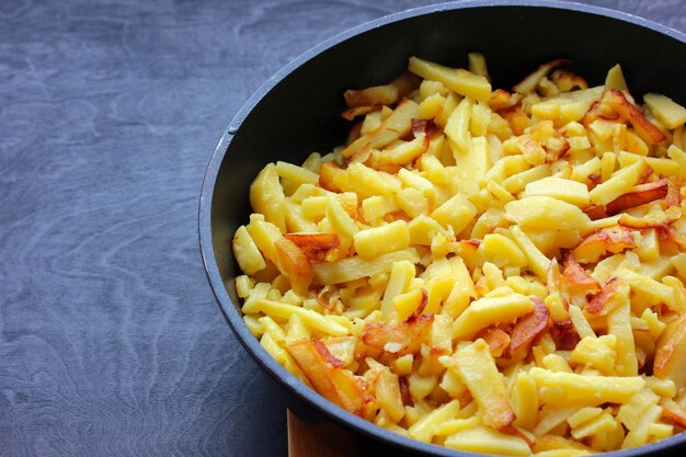 Patate fritte in una padella primo piano su un tavolo nero Cibo fatto in casa