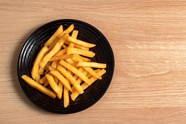 Patate fritte su una banda nera su una tavola di legno