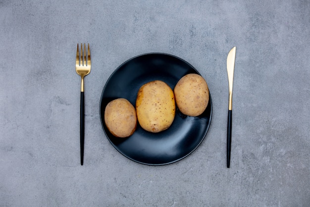 Patate in un piatto con coltello e forchetta