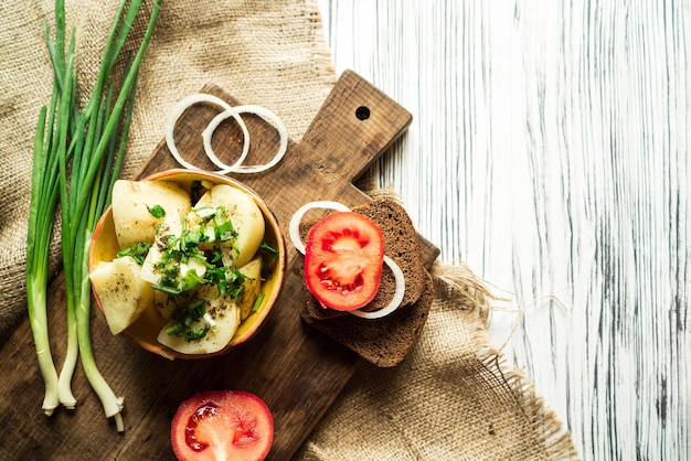 Patate pane di segale cipolla pomodori e verdure su un tavolo bianco 2