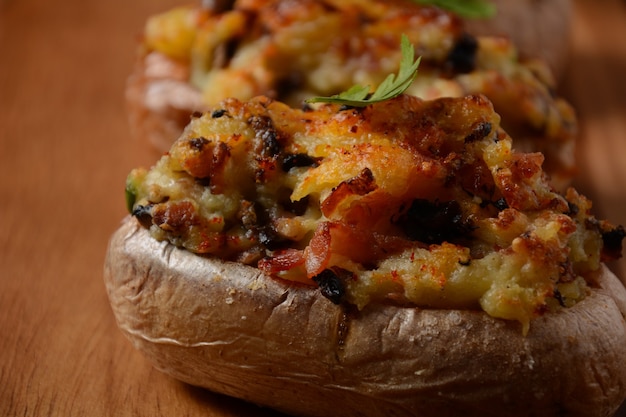 Patate ripiene al forno con pancetta, cipolla verde, funghi e formaggio su una tavola di legno. Stile rustico
