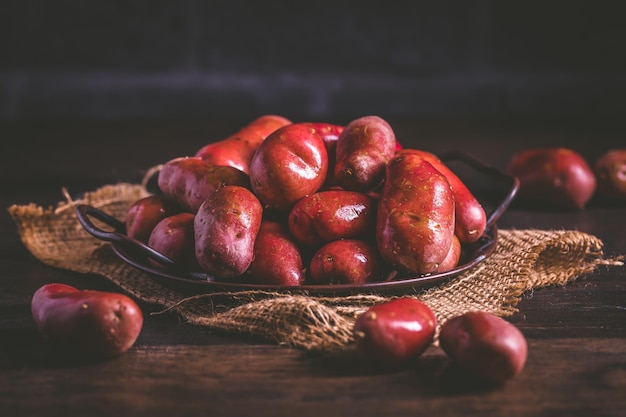 Patate rosse crude organiche su fondo di legno