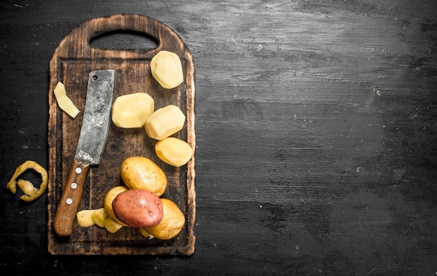 Patate sbucciate con un coltello su un vecchio tagliere