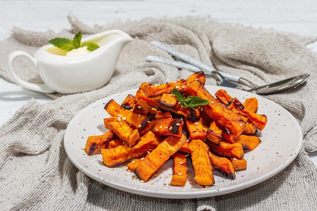 Patatine fritte biologiche al forno con spezie e salsa Porzione e posate servite di verdure dolci