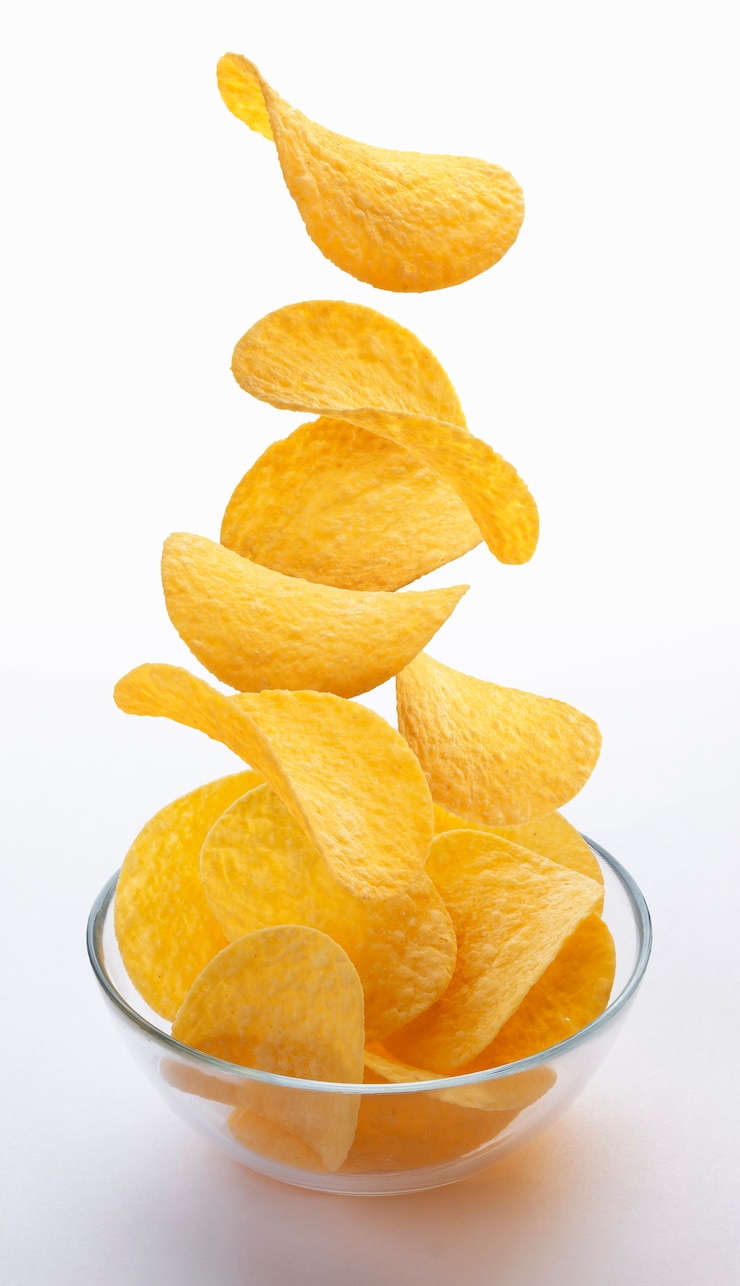 Foto patatine fritte che cadono nella ciotola di vetro isolata su bianco