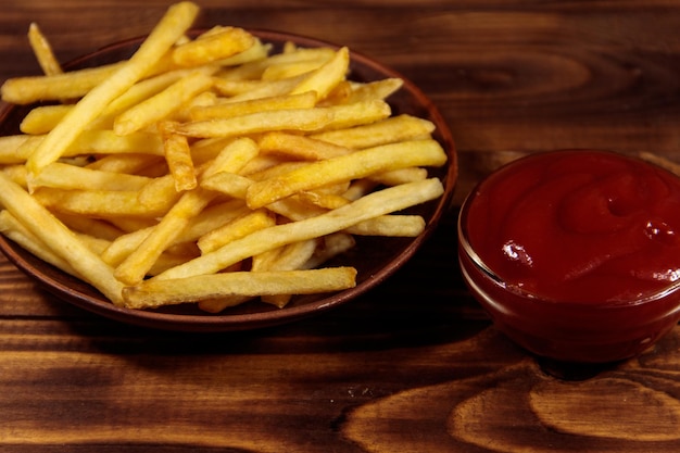 Patatine fritte con ketchup su tavola di legno