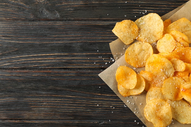 Patatine fritte con sale e carta artigianale su legno, vista dall'alto e spazio per il testo