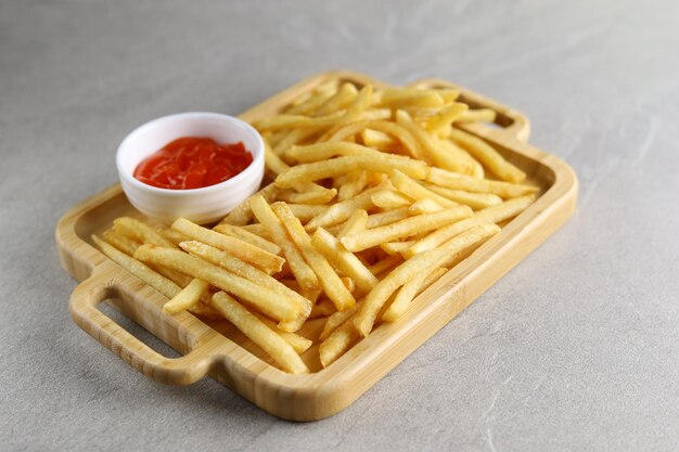 Patatine fritte con salsa su un piatto di legno isolato con sfondo grigio