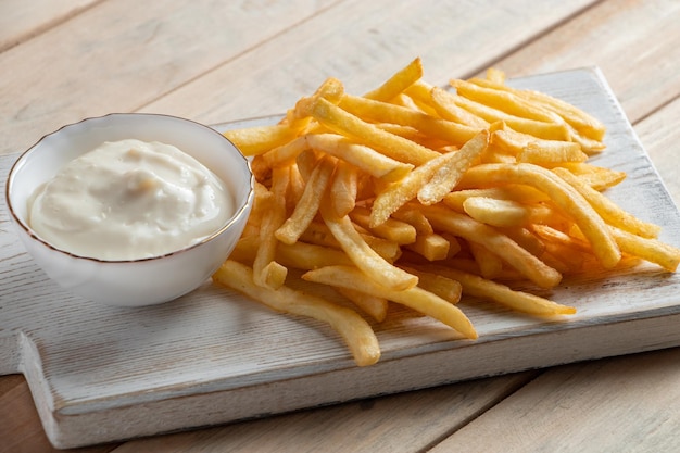 Patatine fritte dorate calde con salsa su sfondo di legno Cibo rustico fatto in casa