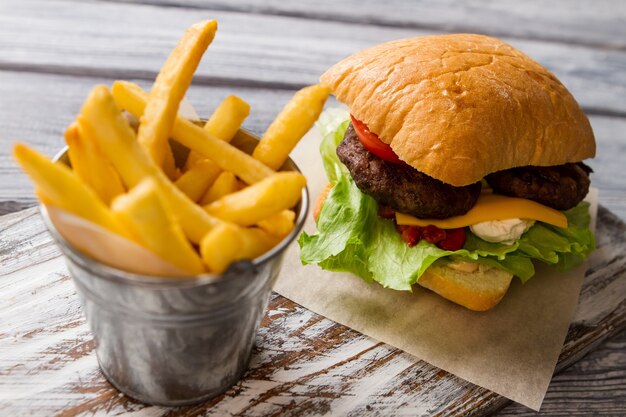 Patatine fritte e hamburger. Formaggio e lattuga. Pranzo tipico da fast food. Pericolo per la tua salute.