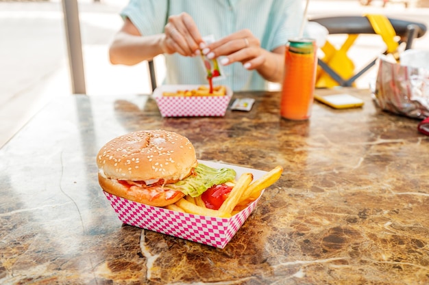 patatine fritte e un hamburger americano fresco sul tavolo con ketchup cibo di strada e concetto di fast food