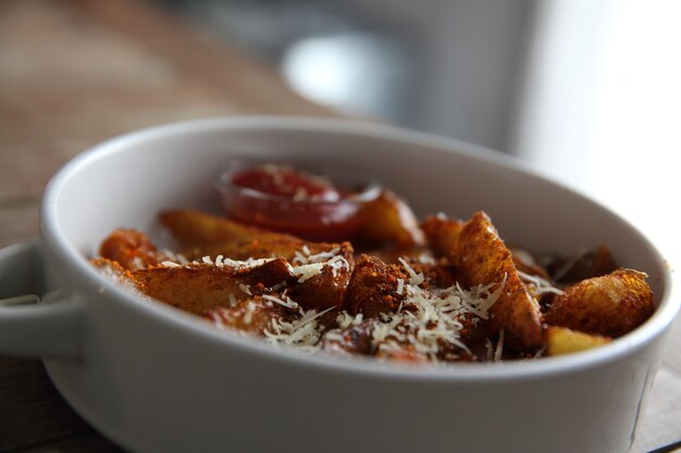 Patatine fritte fresche con ketchup su fondo di legno