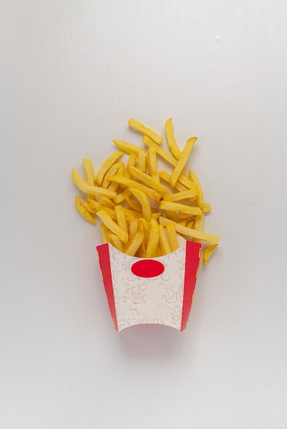 Patatine fritte fresche di patate spazzatura escono dalla scatola di carta su sfondi colorati