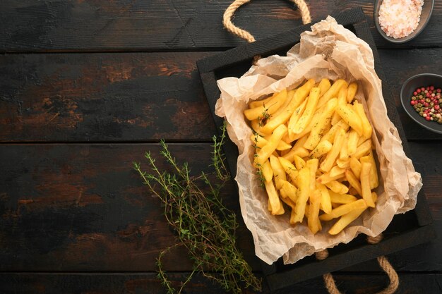 Patatine fritte Gustose patatine fritte server su carta pergamena su tagliere di legno con salsa di pomodoro e formaggio su sfondo vecchio tavolo in legno Diversi piatti Keto Fast food e concetto di cibo malsano