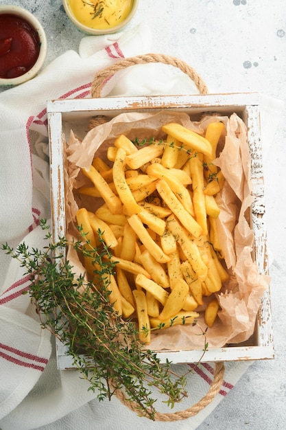 Patatine fritte Gustose patatine fritte server su carta pergamena su tagliere di legno con salsa di pomodoro e formaggio su vecchio sfondo di cemento grigio Diversi piatti Keto Fast food concetto di cibo malsano