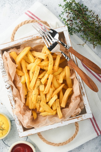 Patatine fritte Gustose patatine fritte server su carta pergamena su tagliere di legno con salsa di pomodoro e formaggio su vecchio sfondo di cemento grigio Diversi piatti Keto Fast food concetto di cibo malsano