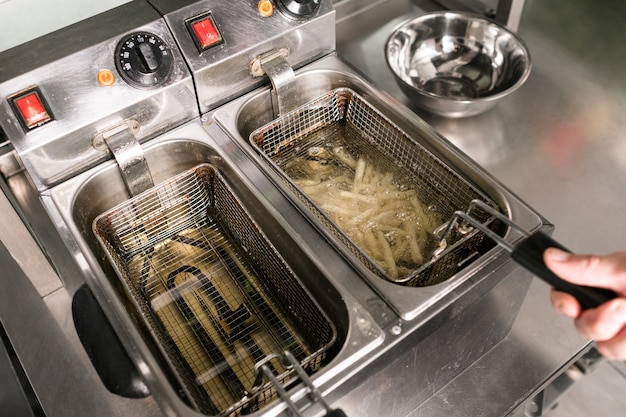 Patatine fritte: il miglior cibo spazzatura di sempre. Cuocere preparando fast food nella cucina del ristorante.