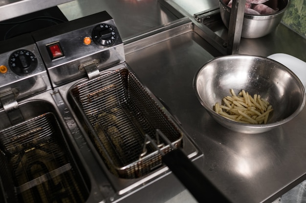 Patatine fritte: il miglior cibo spazzatura di sempre. Cuocere preparando fast food nella cucina del ristorante.