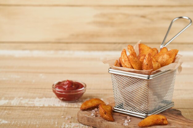 Patatine fritte in cesto di filo metallico con sale e ketchup su sfondo chiaro in legno vecchio clous up Patate fritte Fast food e concetto di cibo malsano