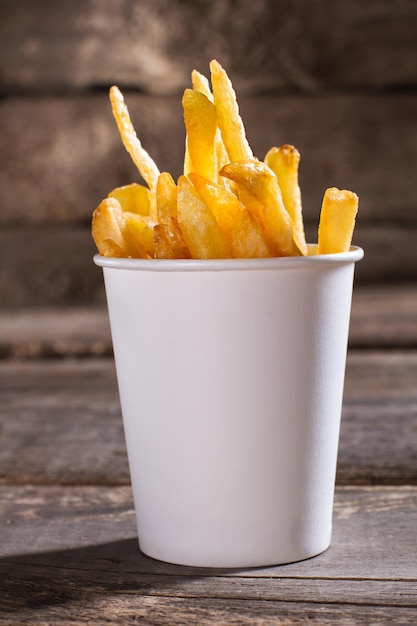 Patatine fritte in tazza di carta Patatine fritte su fondo di legno marrone Dimensione della porzione nella caffetteria Spuntino gratuito per i clienti del bistrot