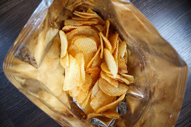 Patatine fritte in un sacchetto di snack aperto da vicino sul pavimento del tavolo