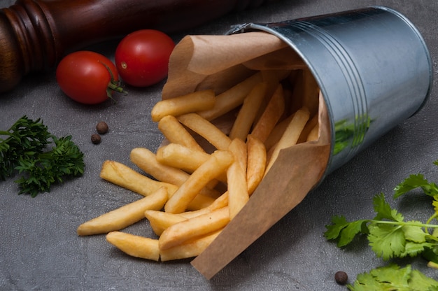 Patatine fritte in un secchio di metallo su sfondo grigio