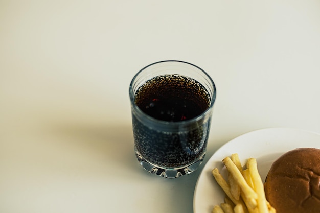 Patatine fritte nel piatto bianco con souse e soda in vetro