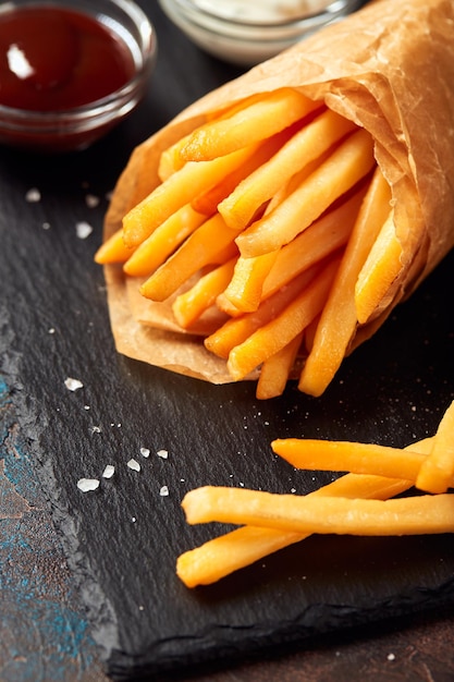 Patatine fritte saporite sul tagliere sul fondo della tavola di legno