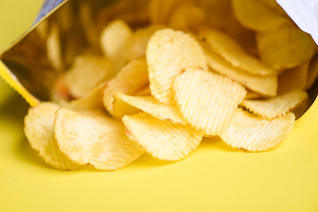 Patatine fritte su sfondo giallo Le patatine sono uno spuntino in un sacchetto avvolto in plastica pronto da mangiare e cibo grasso o cibo spazzatura