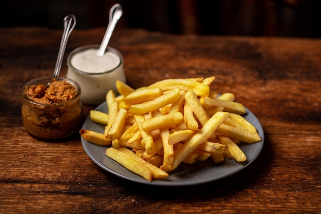 Patatine fritte su un piatto su uno sfondo di legno Maionese e salsa stanno fianco a fianco Cibo vegetariano