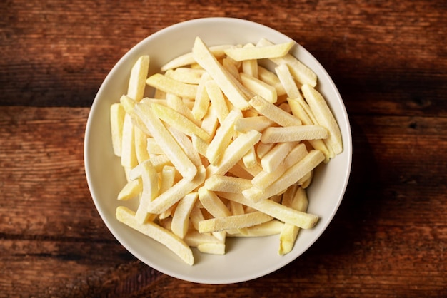 Patatine fritte surgelate su un piatto su uno sfondo di legno Semilavorato di patate surgelate