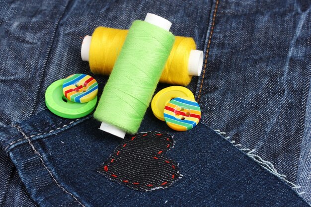 Patch a forma di cuore su jeans con fili e bottoni da vicino