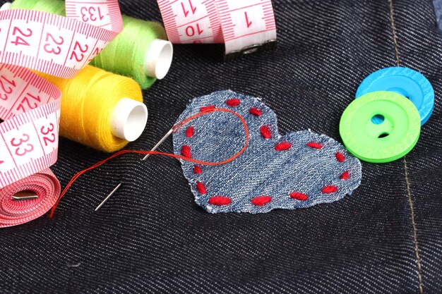 Patch a forma di cuore su jeans con fili e bottoni da vicino