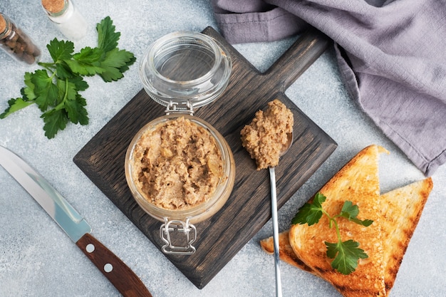 Patè di fegato di pollo fatto in casa in un barattolo di vetro su un tavolo di cemento grigio